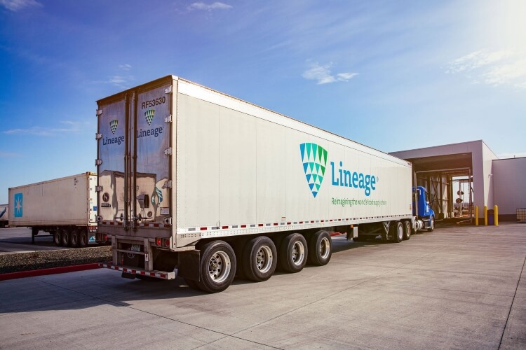 Lineage refrigerated trucks at a loading dock under a bright sky, highlighting the company's commitment to maintaining the cold chain integrity in food logistics.