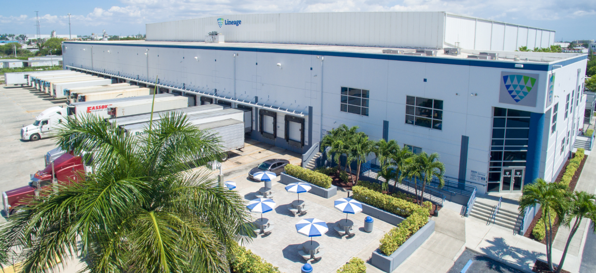 Aerial view of Lineage Logistics cold storage facility in Miami showcasing the expansive warehouse, loading docks with trucks, and the landscaped outdoor area with shaded seating.