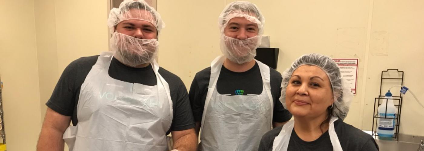Three Lineage volunteers pose for a photo while scooping pepperoni at a food bank